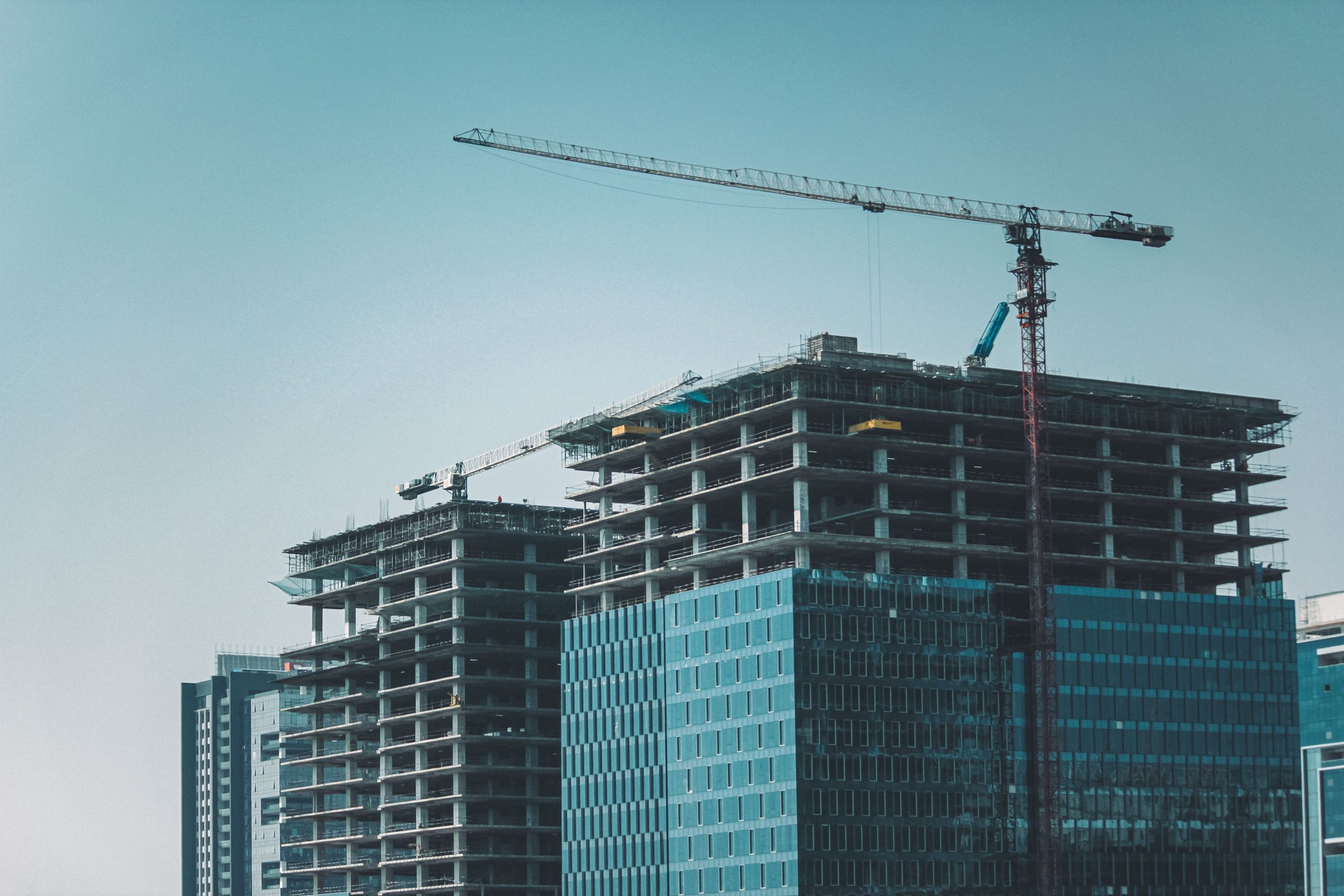 Skyline view of modern skyscrapers under construction with cranes against a clear sky.